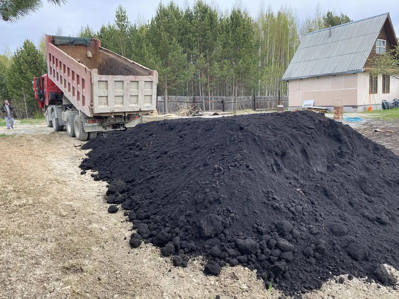 КамАЗ высыпает землю вдоль участка под отсыпку и планировку
