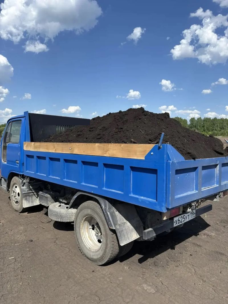 Загруженный самосвал с чернозёмом на площадке перед выездом на участок